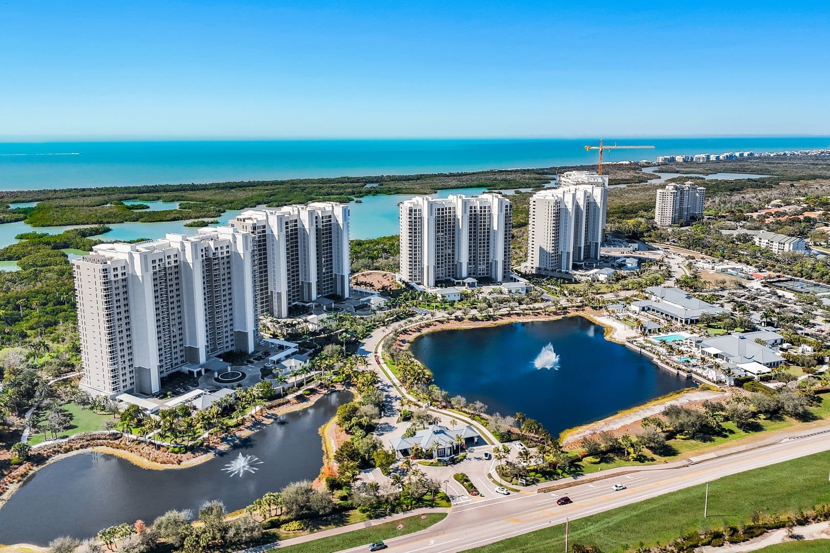 Kalea Bay community lake and entry drive with the Gulf of Mexico beyond the towers