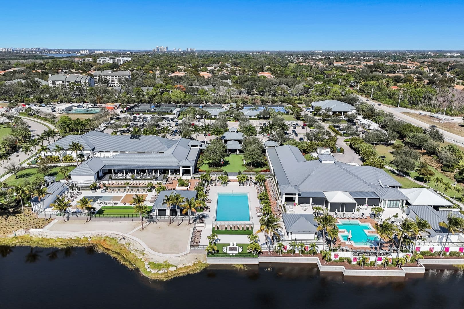 Aerial view of the Club at Kalea Bay clubhouse with the resort pool decks and lakefront in North Naples